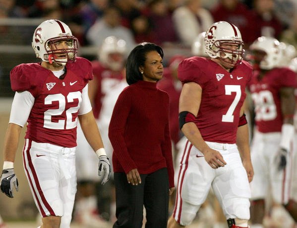 Condoleezza Rice, alongside Bo McNally (22) and Toby Gerhart (7), prepares to perform the cerimonial coin flip