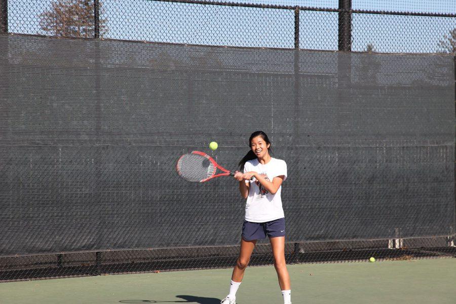 Senior Madeline Lee , co-captain, of the girls’ tennis team, practices her backhand by returning a .shot from a fellow teammate