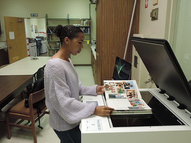 Volunteer Rachel Price scans old yearbook with new, large format scanner, helping digitize the history of Paly’s publications.