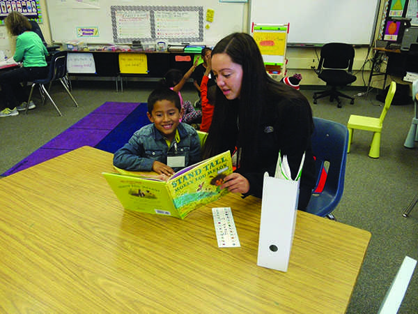 Paly junior Quinn Knoblock reads to a student as a part of Project Rally, an initiative pairing volunteer tutors with kindergarten and first grade students from East palo Alto.