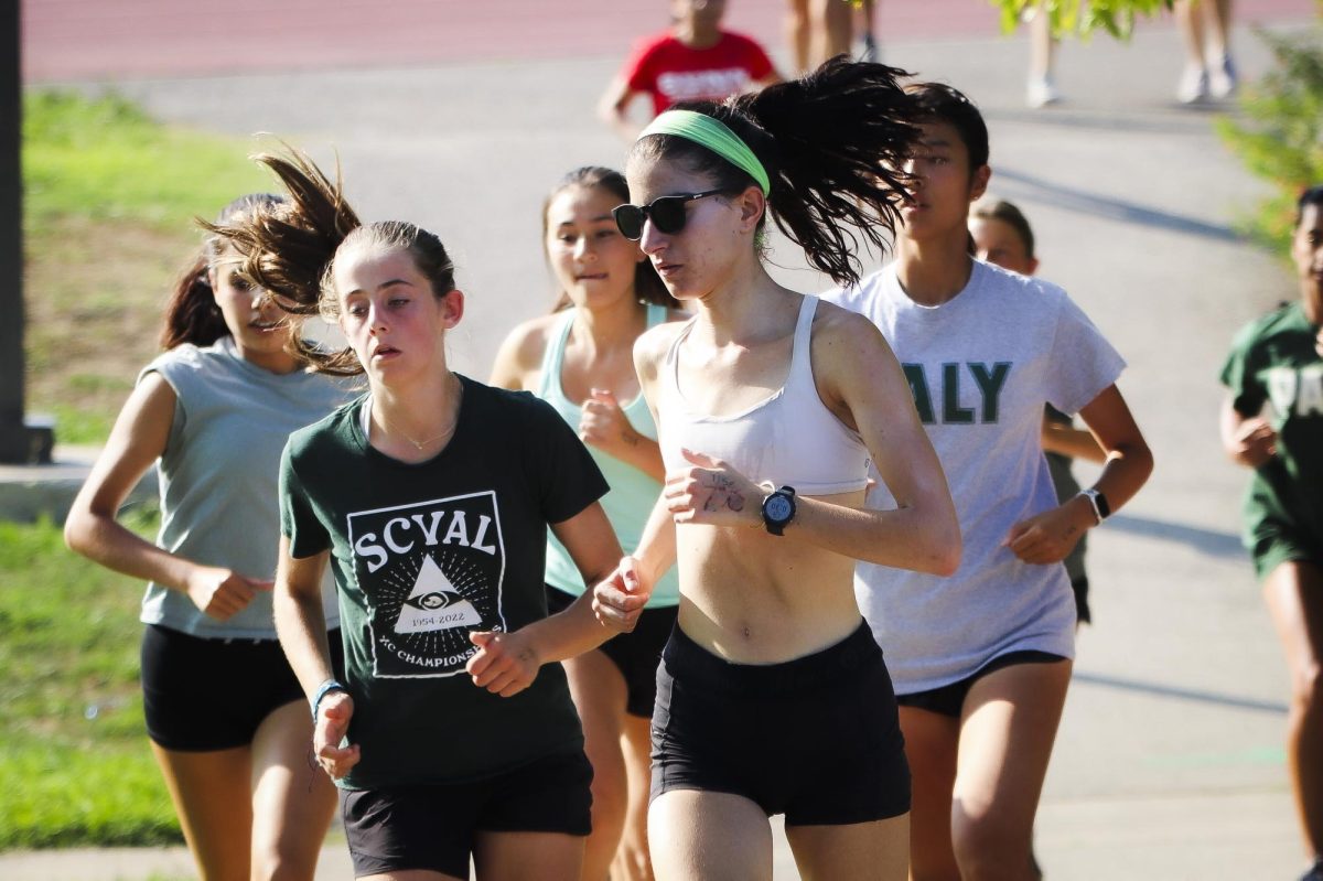 Senior Allie Difede runs alongside junior Romy Kiessling at a Gunn cross country scrimmage on Aug. 31. “The smoke was kind of an issue, and it was also really hot,” junior Kinga Czajkowska said.