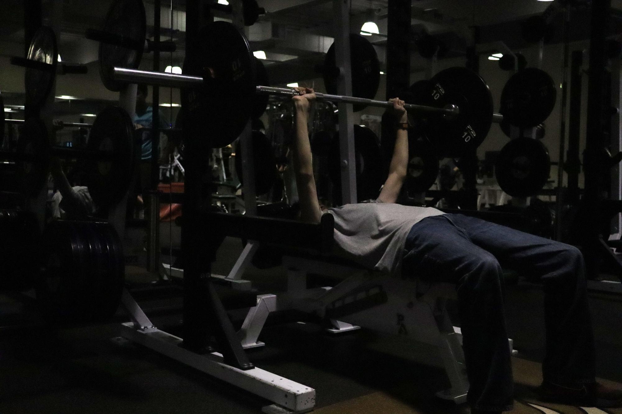 A student bench presses in the Paly weight room. “The workouts help us get stronger and faster,” junior Isaiah Walker said. “In game, it’s helping us. Also, working out just prevents injuries.”
