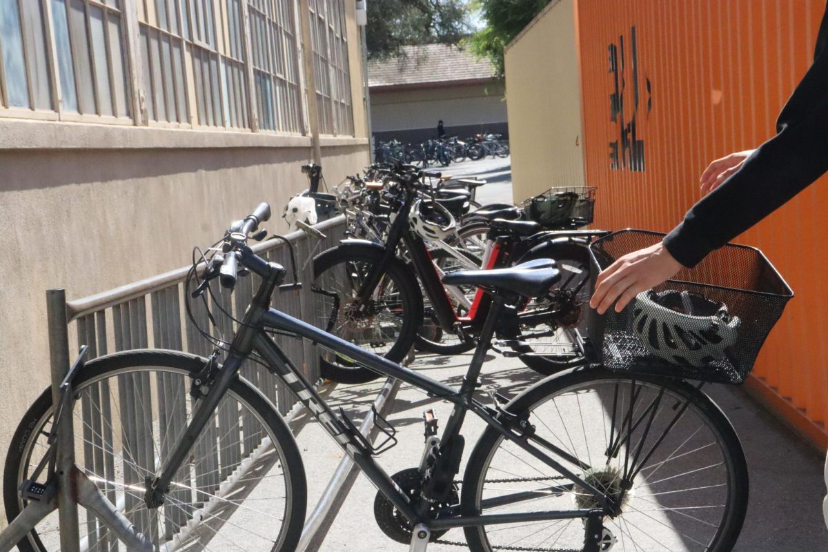A student reaches for their bike as the Palo Alto Transportation Management Association (PATMA) expands Bike Love, a program that rewards Palo Alto workers for biking to work. “Encouraging behavior change to more sustainable transportation options is about more than providing information,” PATMA executive director Justine Burt said.